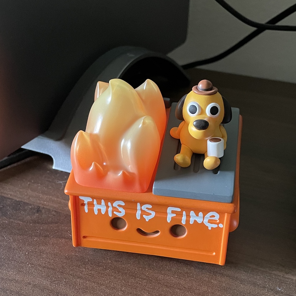 figurine of combination of dumpster fire and "this is fine" memes